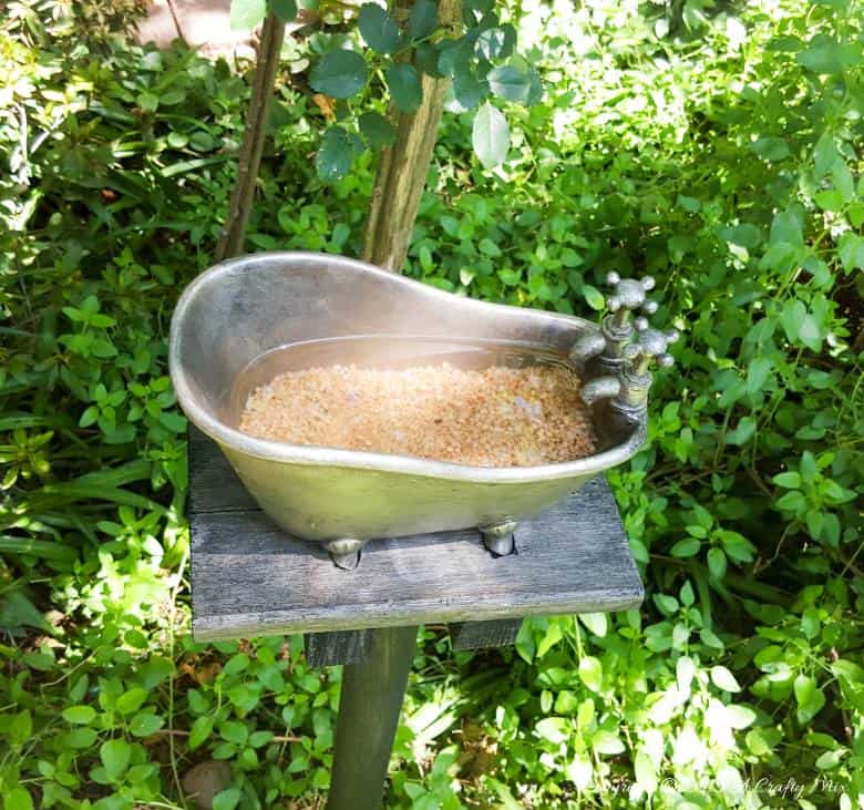 How to repurpose a bathroom accessory into a unique bird bath feature. #DIYOutdoors #BirdBathDIY #ACraftyMix #GardenFeature #Repupose