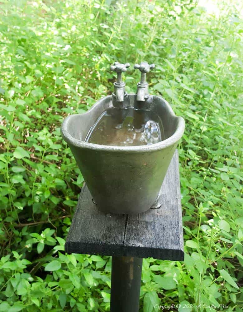 How to repurpose a bathroom accessory into a unique bird bath feature. #DIYOutdoors #BirdBathDIY #ACraftyMix #GardenFeature #Repupose