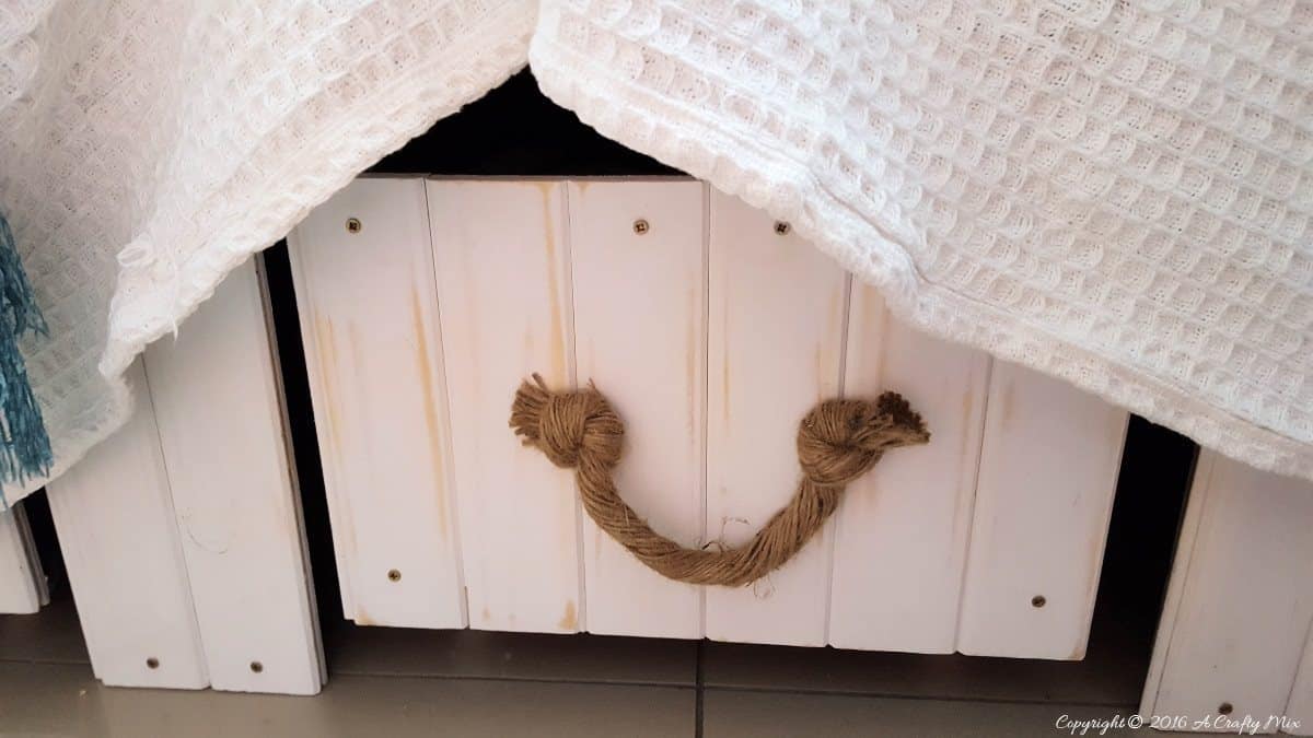 Repurpose crates with mock wooden fronts act as storage under the window seat