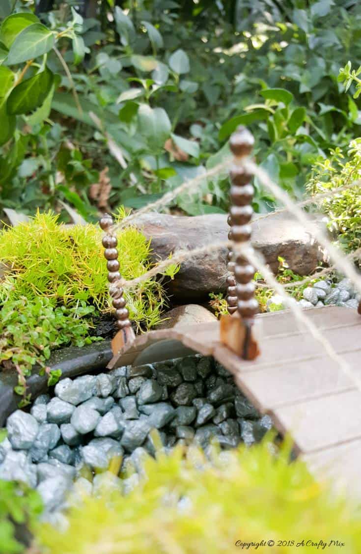 Miniature fairy garden bridge with hanging lantern made from a recycled plastic cup