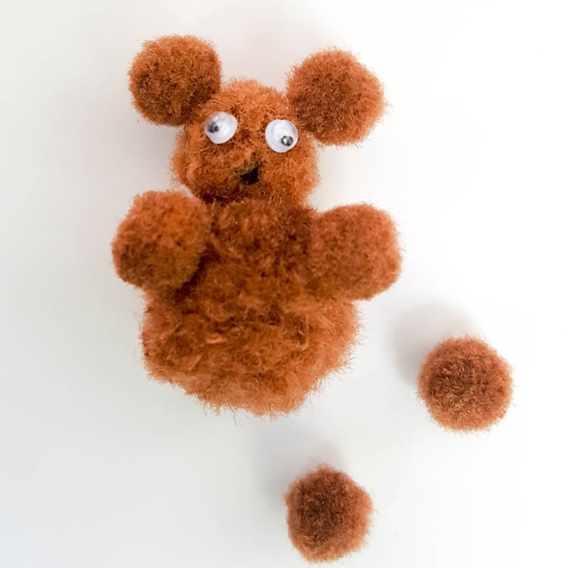 Glue the pompom arms onto the side of the body