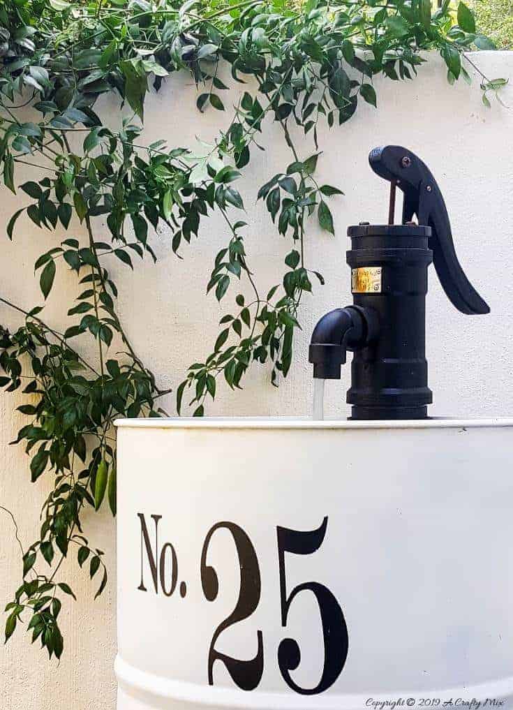 How to turn an empty drum into a unique water feature complete with a faux hand water pump made from PVC pipes The poor hubby grinding away at the drum to create a hole for the old sink #drumwaterfeature #PVChandpump #DIYTutorial #ACraftyMix