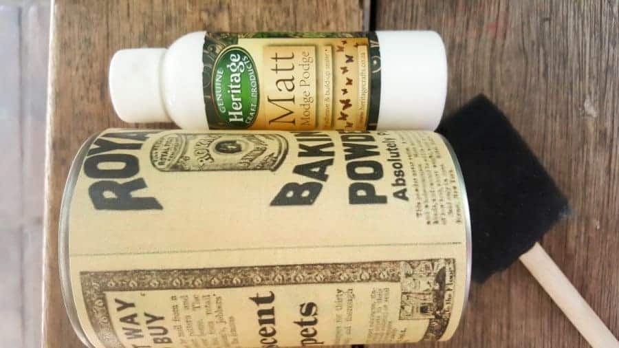 Mod Podge the antique ad prints on the tin cans. #BrownThumb #WoodenCacti #DIYTutorial #ACraftyMix