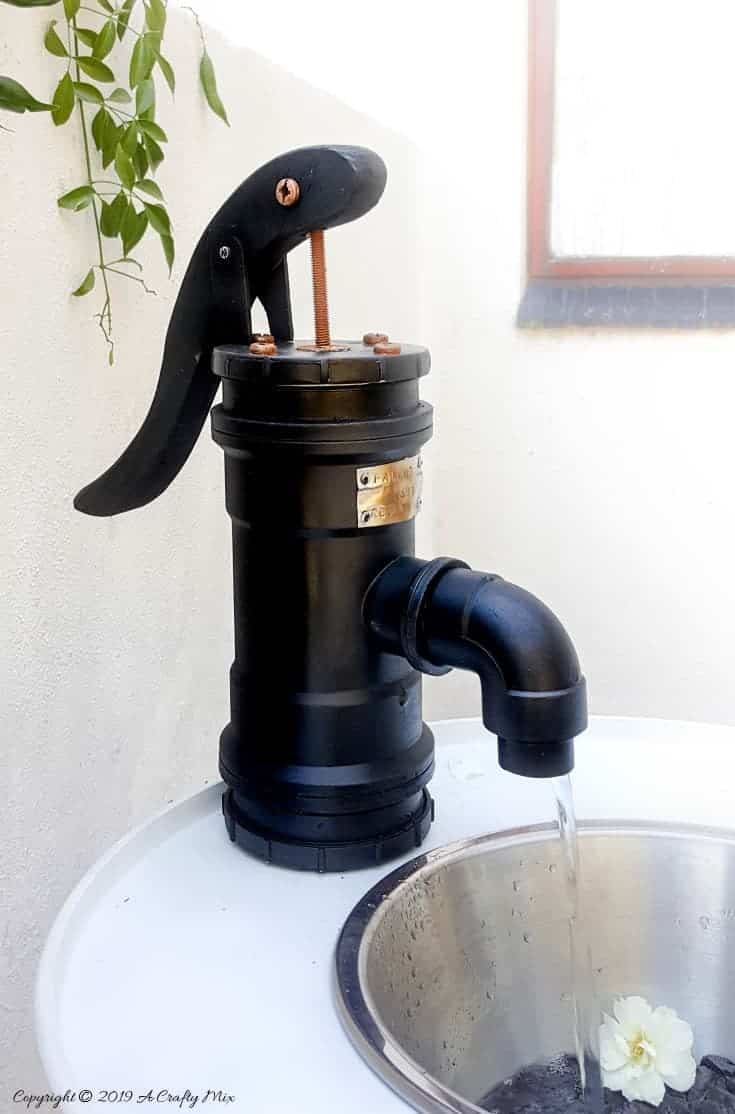 A side view of the pump with water flowing nicely through the spout on the drum water feature #drumwaterfeature #PVChandpump #DIYTutorial #ACraftyMix