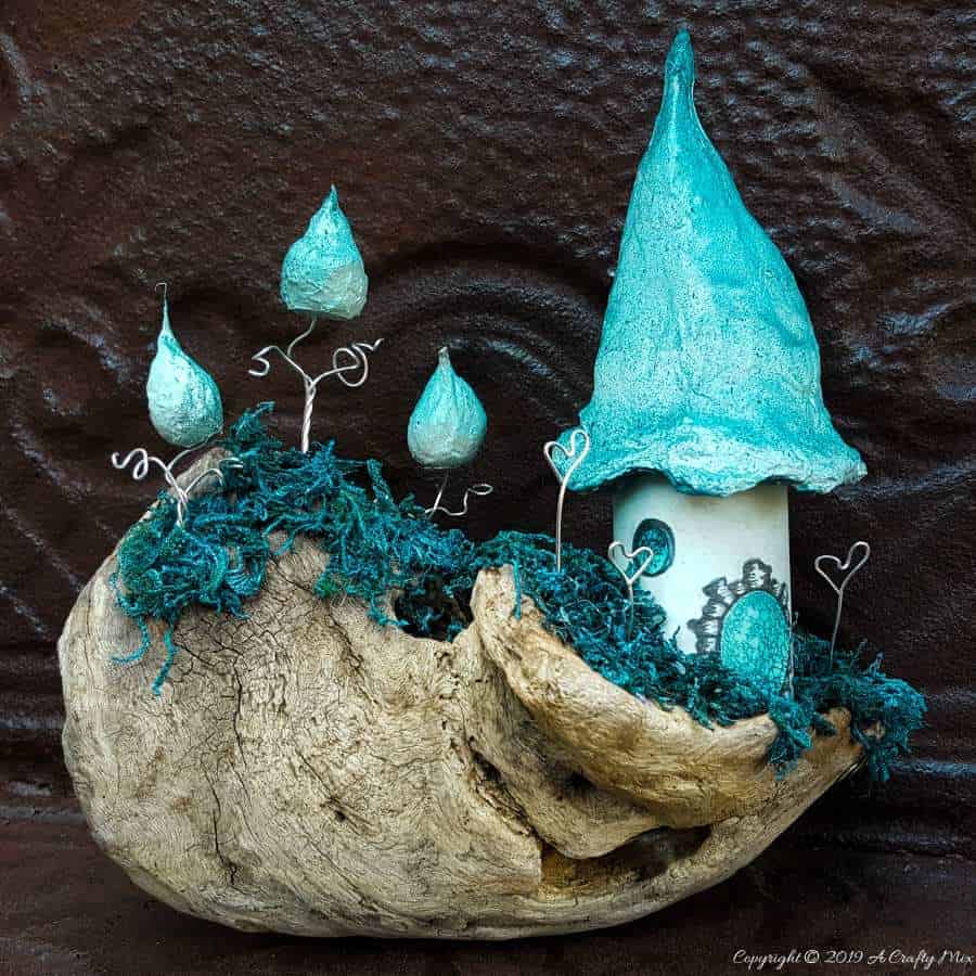 A little fairy home made from a cardboard tube and cotton wool. Add a few whoville inspired trees to make an unusual fairy scape #FairyGarden #FairyScape #FairyTutorial #ACraftyMix #CraftTutorial #FairyCraft