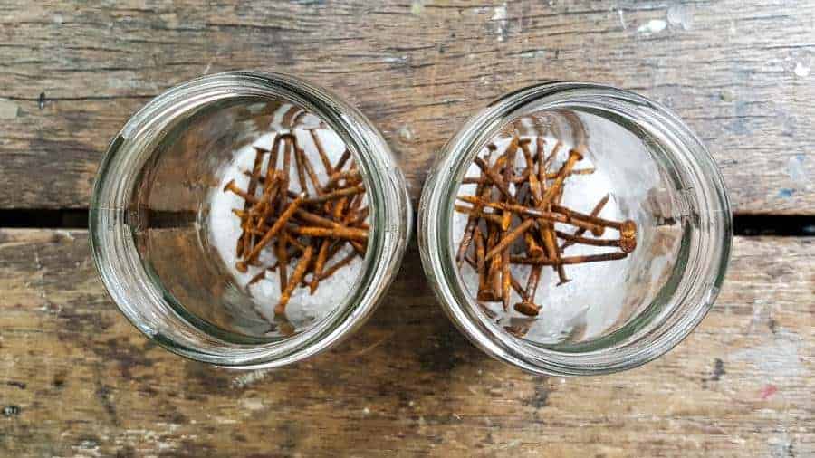Pour 2 tablespoons of coarse salt into the jars and add the rusty nails #Naturalwoodstain #DIYWoodStain #Agingwoodstain #acraftymix #rustynail #weatherwoodstain