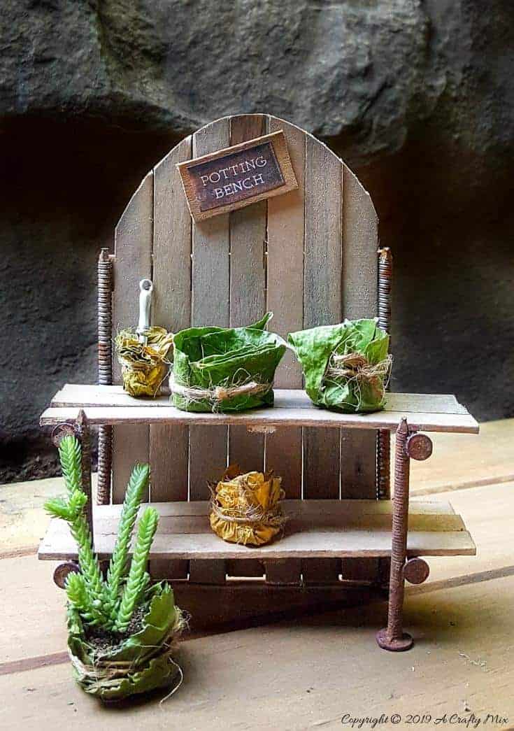 Make this adorable fairy potting bench using rusty nails and stirrer sticks. Quick and easy craft idea for your miniature garden #FairyPottingBench #FairyDIYCrafts #ACraftyMix #FairyGardens #FairyCrafts #WhimsicalFairyCrafts #SimpleFairyCrafts #MiniaturePottingBench #RustyNails