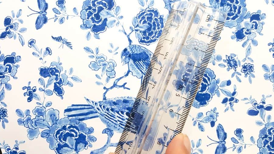 Use a ruler or a credit card to smooth the the vinyl tiles on  #ChinoiserieDecor #VinylTile #EasyMakeOver #HomeDecorDIY #chinoiserietiles #ACraftyMix #blueandwhitedecor #chinoiseriechic #VinylTileDecor #DIYTutorial
