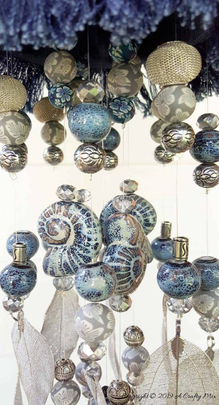 The different metals and types of beads create a unique sound #DIYDenim #DenimIdeas #DenimMobile #DenimUpcycleIdeas #ACraftyMix #DenimUpcycle #DIYWindChime #TinCanRecycle #TinCanMobile #DenimWindChime