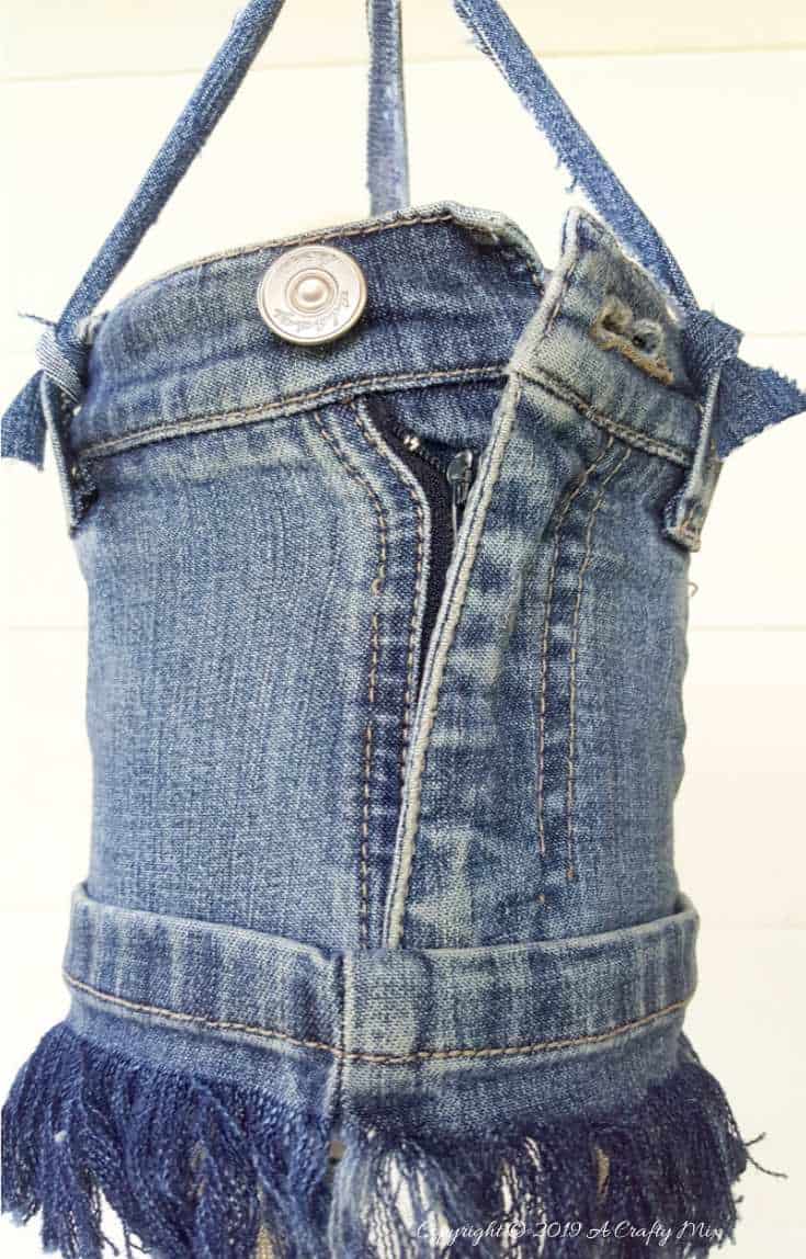 Using interesting pieces from an old pair of jeans adds visual interest to the upcycled denim wind chime #DIYDenim #DenimIdeas #DenimMobile #DenimUpcycleIdeas #ACraftyMix #DenimUpcycle #DIYWindChime #TinCanRecycle #TinCanMobile #DenimWindChime