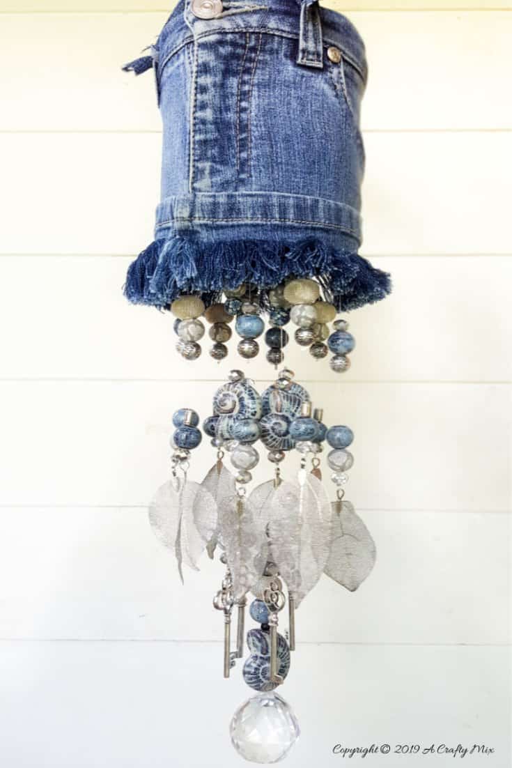 How to make an upcycled denim wind chimes using a tin can and an assortment of beads and metal charms. #DIYDenim #DenimIdeas #DenimMobile #DenimUpcycleIdeas #ACraftyMix #DenimUpcycle #DIYWindChime #TinCanRecycle #TinCanMobile #DenimWindChime