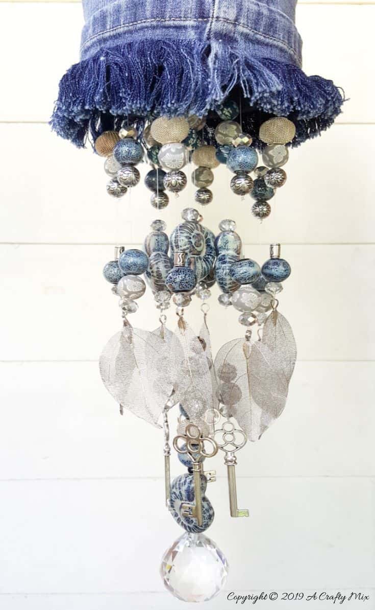 Using a combination of beads and metal charms helps create a unique sound on the upcycled denim wind chimes #DIYDenim #DenimIdeas #DenimMobile #DenimUpcycleIdeas #ACraftyMix #DenimUpcycle #DIYWindChime #TinCanRecycle #TinCanMobile #DenimWindChime