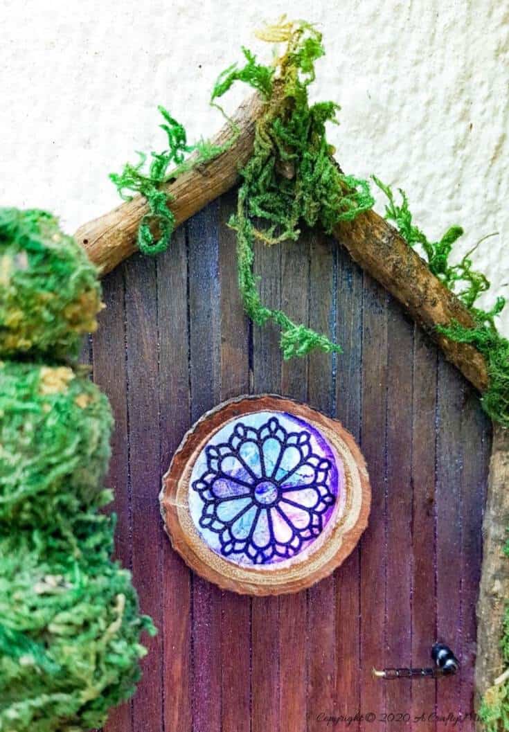 Welcome the fae folk into your home with this gorgeous stained glass fairy door. Made with things you probably already have in your craft cupboard the door doubles up as a night light. #FairydoorDIY #FairyDoorIdeas #ACraftyMix #MakeAFairyDoor #MiniatureStainedGlass #AlcoholInk
