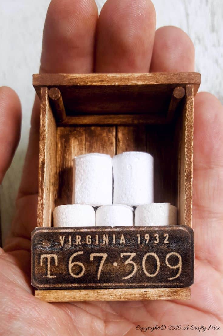 If you&rsquo;re looking to make something unique for your doll&rsquo;s house you&rsquo;re going to love this mini license plate toilet paper holder tutorial. It includes a video that will show you how to make tiny toilet rolls and there&rsquo;s a free printable you can use to create the license plate. #DIYMiniatureToiletPaper #ToiletPaperStorage #ACraftyMix #MakingMiniatures #FairyToiletPaper #DollHouseCrafts