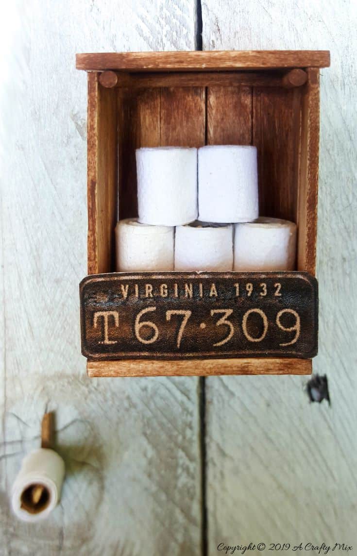 If you&rsquo;re looking to make something unique for your doll&rsquo;s house you&rsquo;re going to love this mini license plate toilet paper holder tutorial. It includes a video that will show you how to make tiny toilet rolls and there&rsquo;s a free printable you can use to create the license plate. #DIYMiniatureToiletPaper #ToiletPaperStorage #ACraftyMix #MakingMiniatures #FairyToiletPaper #DollHouseCrafts