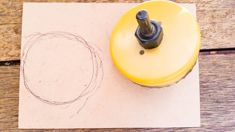 Cut a wooden base for the hollow pumpkin using a hole saw