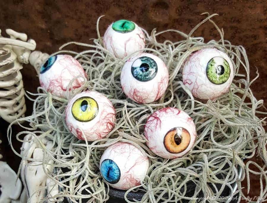 Up the creepy stakes this Halloween and make these realistic eyeballs for Halloween. Quick and budget-friendly they'll add just the right spooky factor to your decor. The tutorial includes free "iris" printables to use #HalloweenDecor #CreepyEyeballs #ACraftyMix #FreePrintables