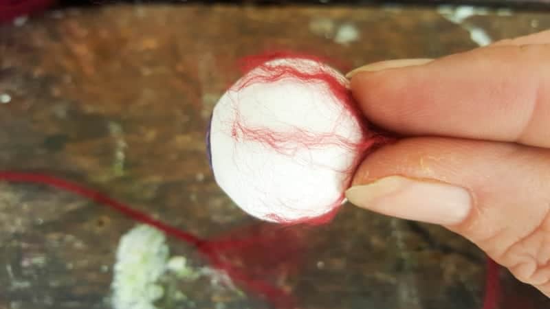 Place the frayed yarn on the back of the eyeball and mod podge it on
