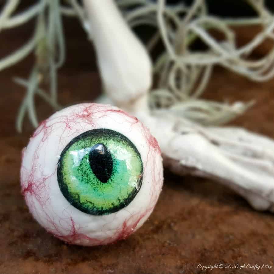 Up the creepy stakes this Halloween and make these realistic eyeballs for Halloween. Quick and budget-friendly they'll add just the right spooky factor to your decor. The tutorial includes free "iris" printables to use #HalloweenDecor #CreepyEyeballs #ACraftyMix #FreePrintables