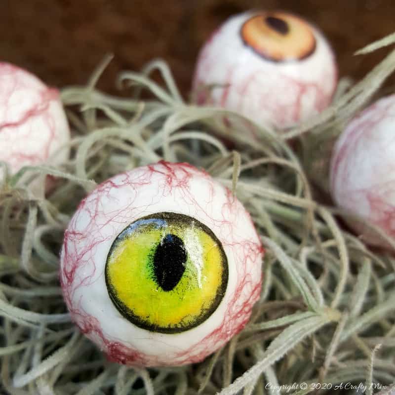 Up the creepy stakes this Halloween and make these realistic eyeballs for Halloween. Quick and budget-friendly they'll add just the right spooky factor to your decor. The tutorial includes free "iris" printables to use #HalloweenDecor #CreepyEyeballs #ACraftyMix #FreePrintables