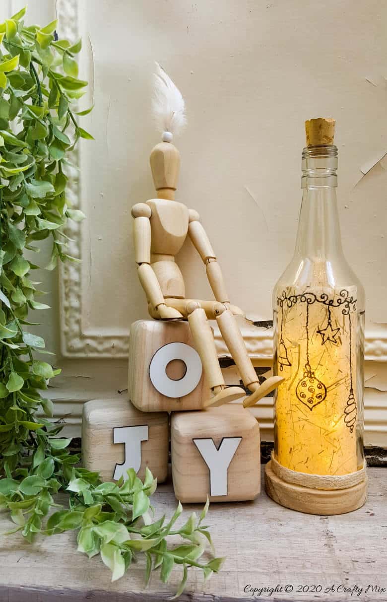 Take your glass bottle light to a whole new level with this DIY idea. A quick and easy way to repurpose and customize ONE bottle to fit any occasion or season with swappable art inserts. And you&rsquo;ll have loads of fun coming up with new images to put inside too. #bottlelight #winebottlelights #acraftymix #bottlerepurpose #bottlecrafts