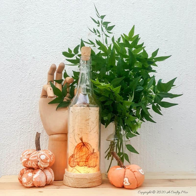 Take your glass bottle light to a whole new level with this DIY idea. A quick and easy way to repurpose and customize ONE bottle to fit any occasion or season with swappable art inserts. And you&rsquo;ll have loads of fun coming up with new images to put inside too. #bottlelight #winebottlelights #acraftymix #bottlerepurpose #bottlecrafts