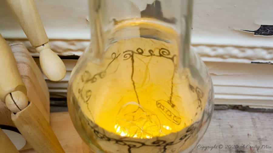 Take your glass bottle light to a whole new level with this DIY idea. A quick and easy way to repurpose and customize ONE bottle to fit any occasion or season with swappable art inserts. And you&rsquo;ll have loads of fun coming up with new images to put inside too. #bottlelight #winebottlelights #acraftymix #bottlerepurpose #bottlecrafts