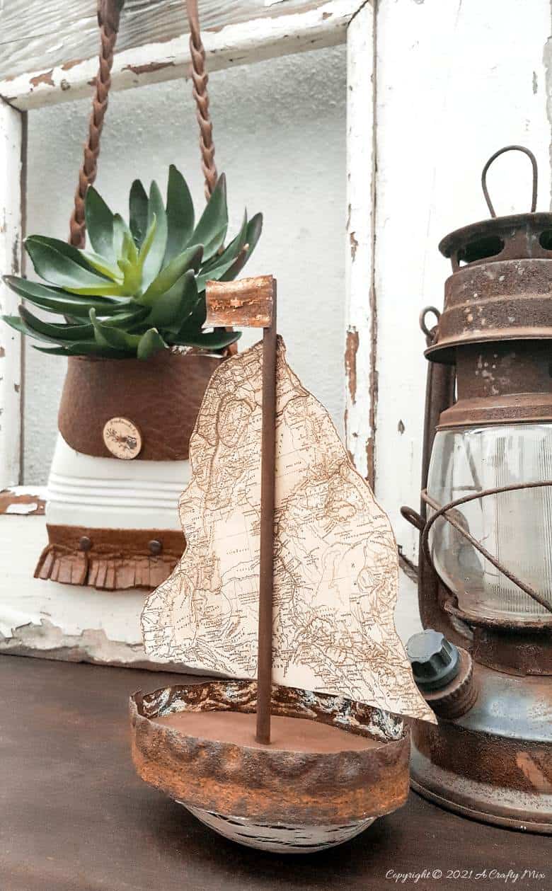 Looking to add some rustic charm to your coastal decor? This avocado sailboat is quick and easy to make and it's budget-friendly too. Customise the little boat and add a map sail of your favorite place or country. #avocadoupcycle #ACraftyMix #coastaldecor #concretedecor