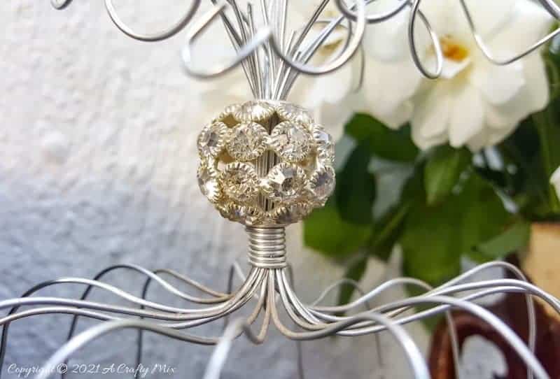 A beautiful crystal bead sits on top of the birdcage. This easy to follow tutorial will show you how to make your own art deco wire bird cage. Made in a morning, it&rsquo;s a fun way to add a little handcrafted glamour to you d&eacute;cor. #BirdCage #DIY #ACraftyMix