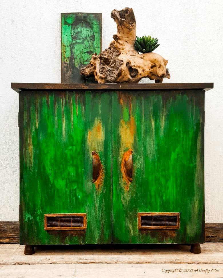 Ever found a cheap melamine cupboard at the thrift store that was just to “bleh” to fit into your décor style? This tutorial will show you how to give it an easy faux distressed metal makeover that won’t break the bank. #melaminmakeover #paintingmelamine #acraftymix #fauxmetal #UnicornSpit
