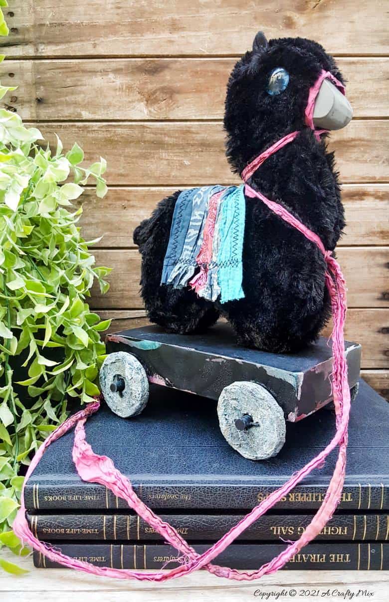 In the tradition of old toys we made this DIY Pull Toy llama using upcycled tin can wheels. This fun recycled craft idea comes with a free printable llama template. #Upcycle #TinCan #ACraftyMix #PullToy #HomeDecor