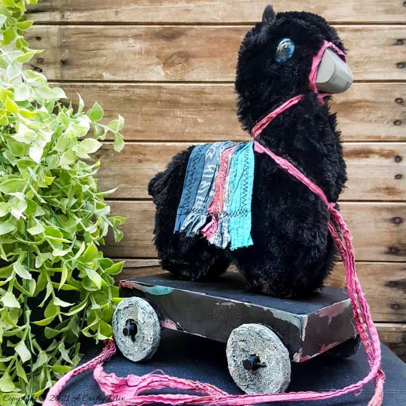 In the tradition of old toys we made this DIY Pull Toy llama using upcycled tin can wheels. This fun recycled craft idea comes with a free printable llama template. #Upcycle #TinCan #ACraftyMix #PullToy #HomeDecor