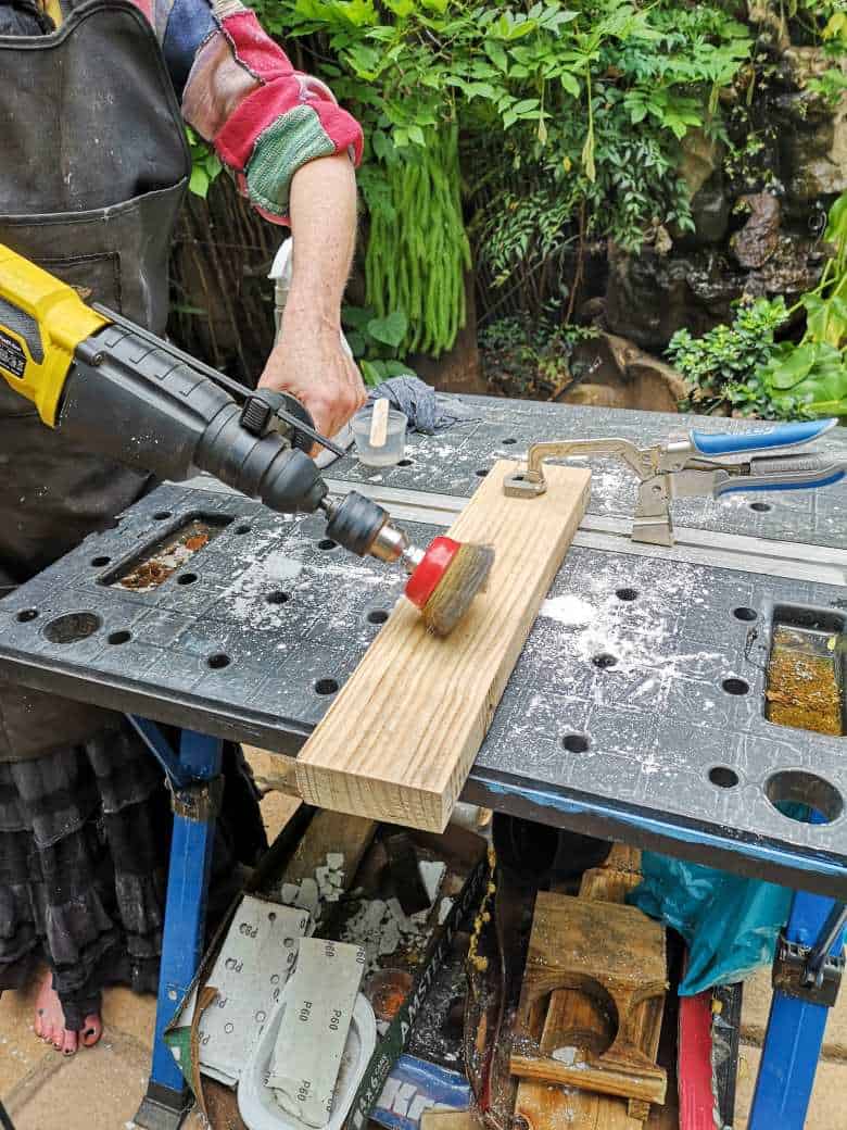 Using a metal brush attached to a drill to distress the frame