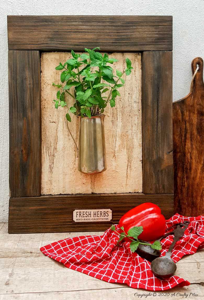 I love this fresh twist on the traditional herb garden. The framed bouquet of fresh herbs can be propped on the counter or hang it up if you prefer to keep your counters clutter free. #IndoorHerbs #IndoorGarden #FramedGarden #ACraftyMix #DistressedWall #DistressedFrame #GardenInspiration#FreshHerbs