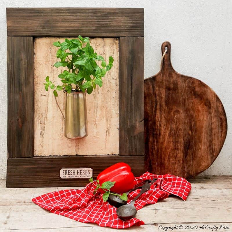 I love this fresh twist on the traditional herb garden. The framed bouquet of fresh herbs can be propped on the counter or hang it up if you prefer to keep your counters clutter free. #IndoorHerbs #IndoorGarden #FramedGarden #ACraftyMix #DistressedWall #DistressedFrame #GardenInspiration#FreshHerbs