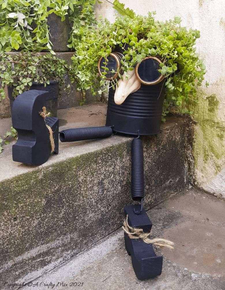 Looking for a creative way to repurpose a tin can? The  you'll love this tin can steampunk planter. We call him Dr Edinose and he's sure to add a little whimsy to your outdoor decor. #steampunkplanter #ACraftyMix #TinCanRecycle