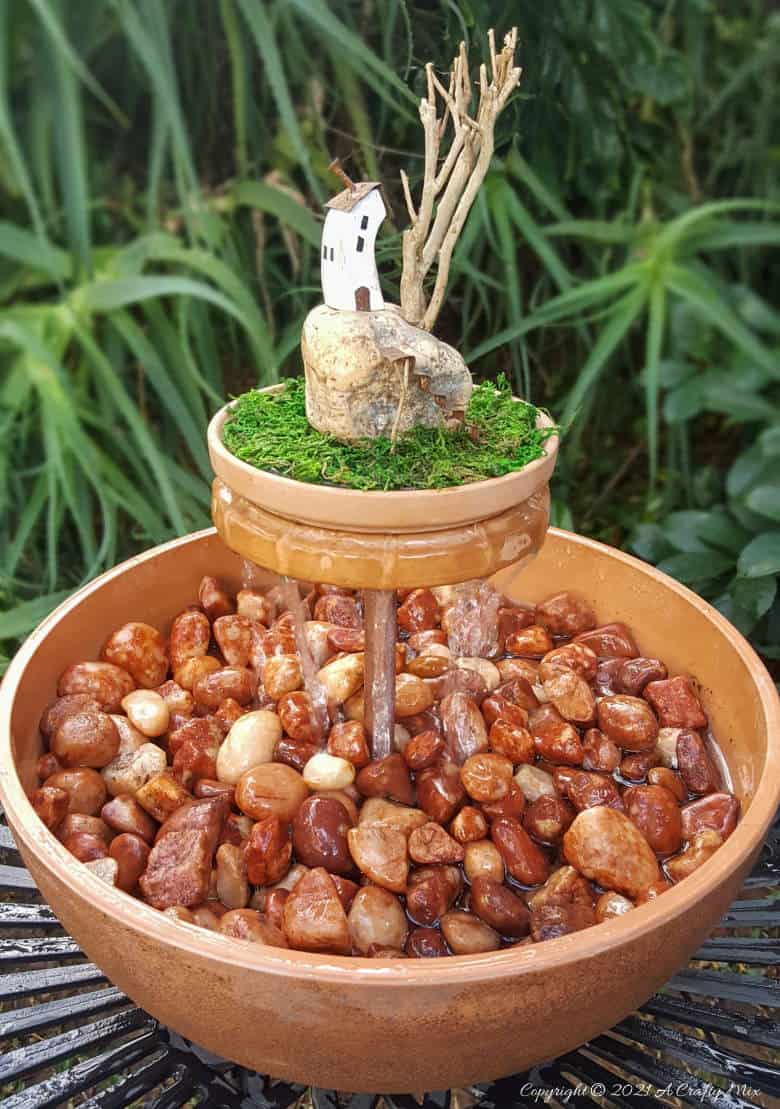 This photo-rich tutorial will show you how just how easy it is to repurpose an empty CD case and turn it in a CD spindle water feature bringing a calming, zen-like decorative feel to any space. #Spindlerepurpose #ACraftyMix #waterfeature