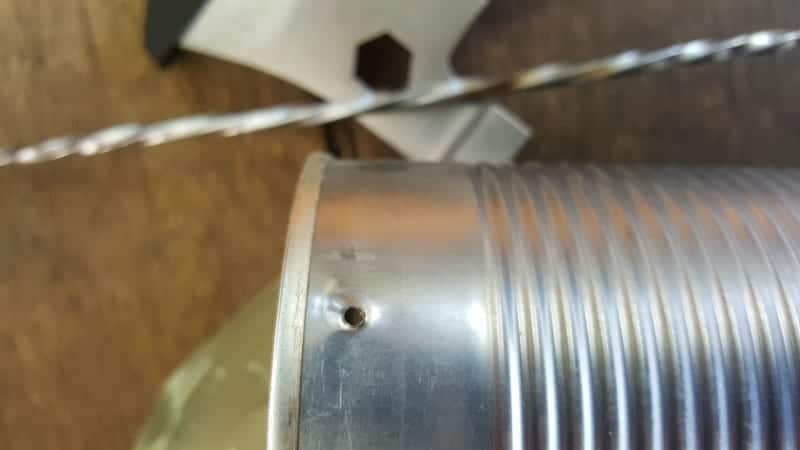 Use a metal skewer (or nail) and hammer to make a hole in the tin can
