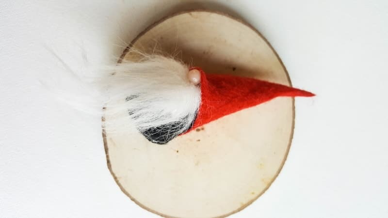 The finished miniature sock gnome on a wood slice
