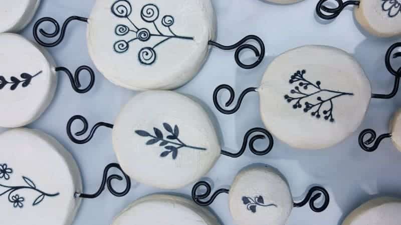A collection of air-dry clay disc with botanical prints that have been tattooed on