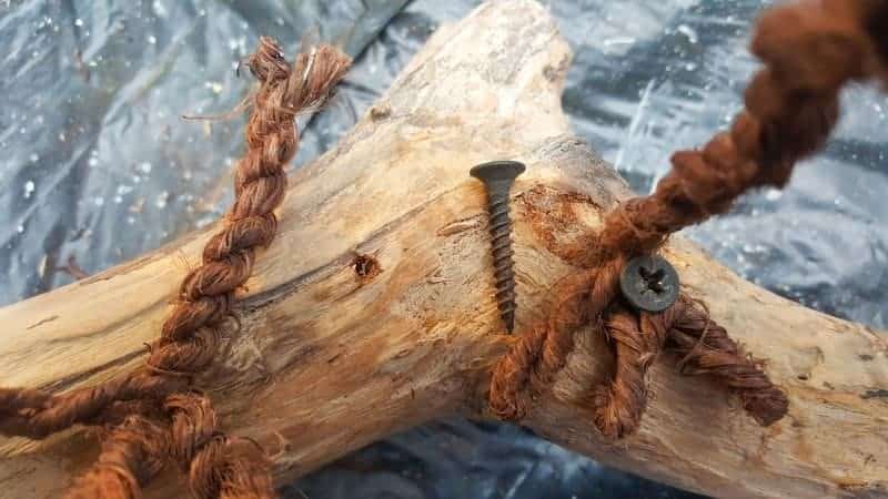 Use wood screws to screw the legs onto the piece of drift wood or branch