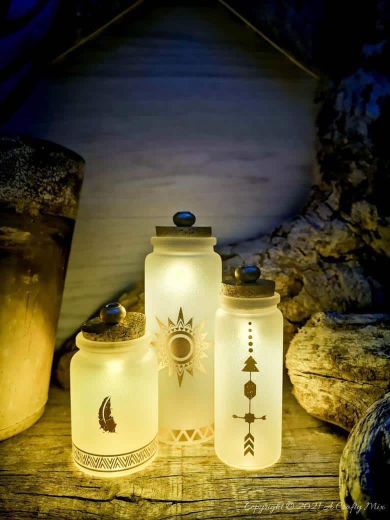 A perfect beginner-friendly home decor project that only takes a few minutes to make! These gorgeous glass bottle lights with gold accents look lovely no matter where you display them. Place them on your mantle or bookshelf or use them as a centerpiece at a special event or bridal shower. #DIYBottleDecor #ACraftyMix #GlassBottleIdeas