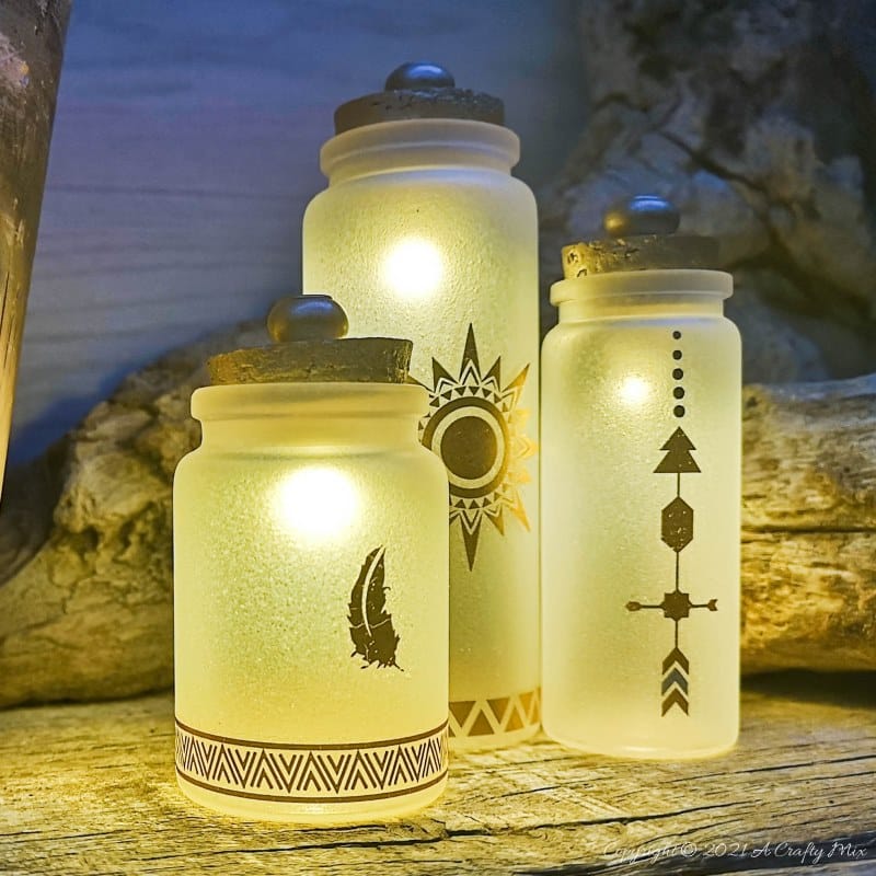 A perfect beginner-friendly home decor project that only takes a few minutes to make! These gorgeous glass bottle lights with gold accents look lovely no matter where you display them. Place them on your mantle or bookshelf or use them as a centerpiece at a special event or bridal shower. #DIYBottleDecor #ACraftyMix #GlassBottleIdeas