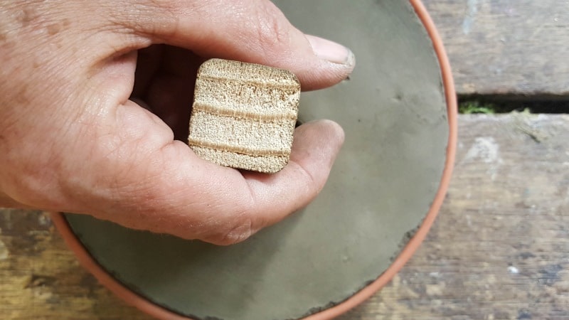 Use the piece of wood to wiggle the button free from the drip tray