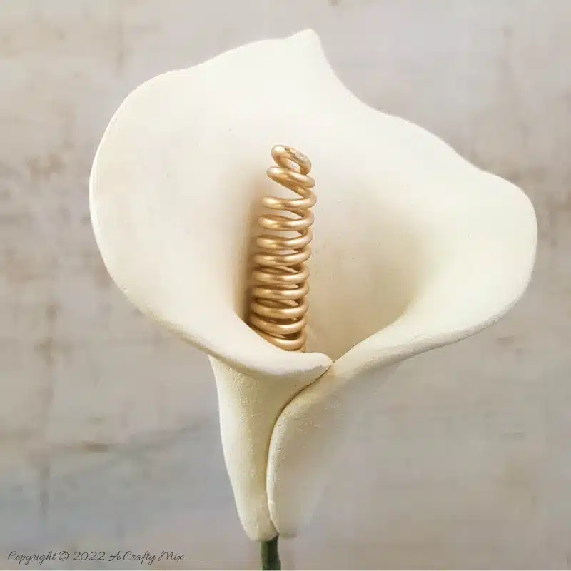 Quick and easy to make, these air dry clay arum lilies with a curly wire spadix are striking on their own or grouped together in a bouquet. Detailed tutorial on the blog with of step-by-step photos and video. #acraftymix #arum #calla