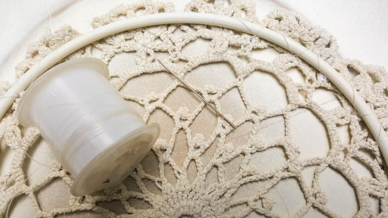 Use clear fishing line to sew the doily onto the hoop