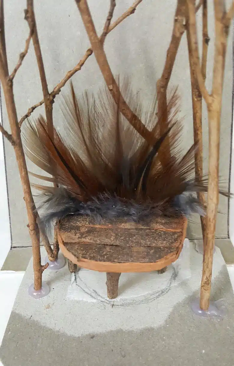 Place the throne on the cardboard template before gluing down the twigs