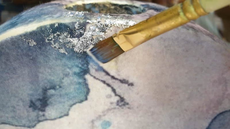 Apply a small a mount of clear glue and add the silver leaf