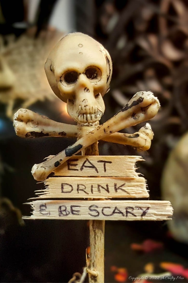 Add a not-so-creepy touch to your All Hallows' Eve Gathering with these easy-to-make skull and crossbones place card holders. They only take a few minutes to put together and will make both your wallet and your dinner guests smile. #ACraftyMix #HalloweenDecor
