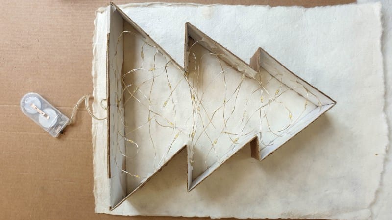 Tape the lights to the inside of the tree frame